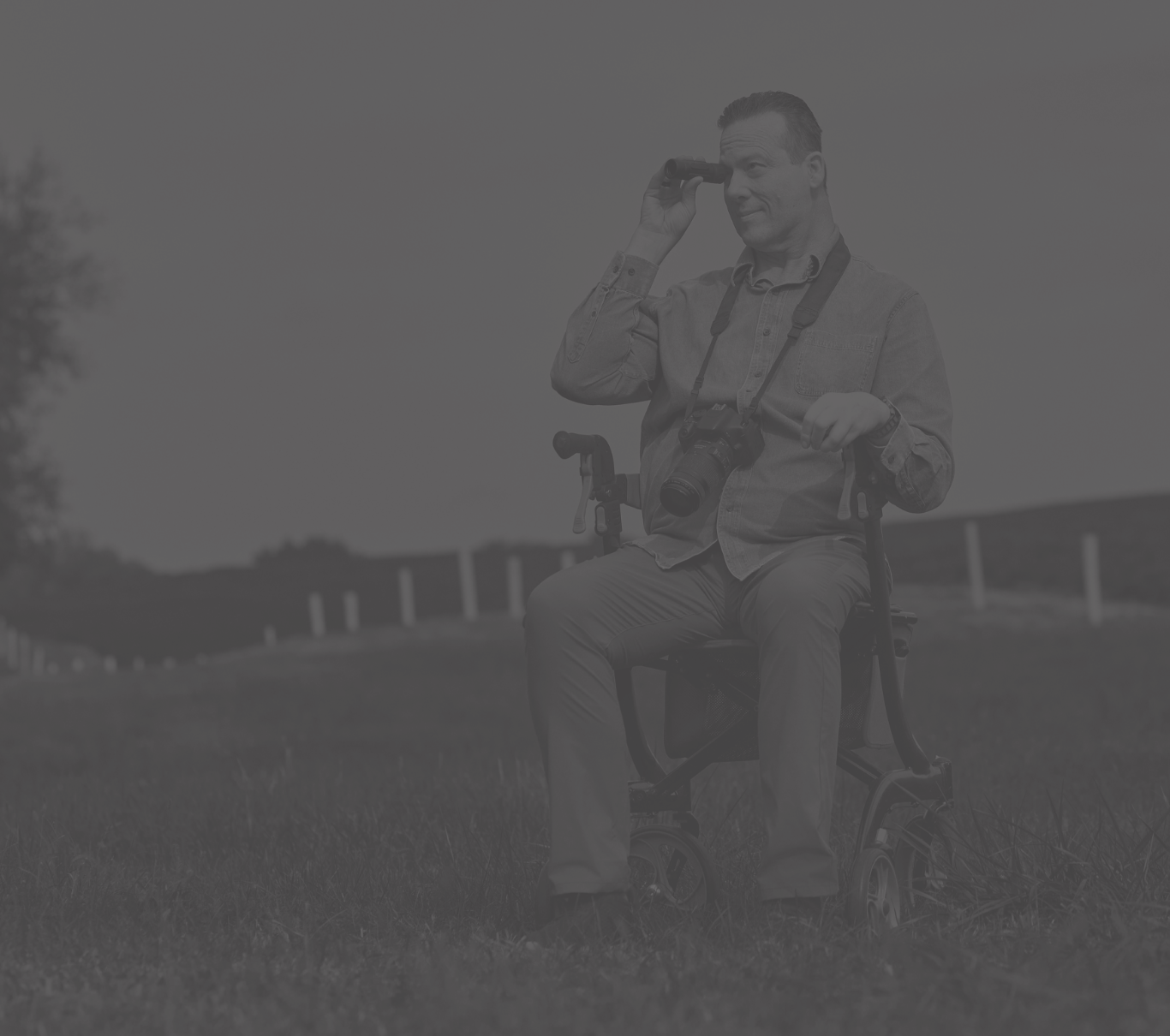 Ambassador Scott, who has LOPD, sitting in a wheelchair while taking a photo with his digital camera
